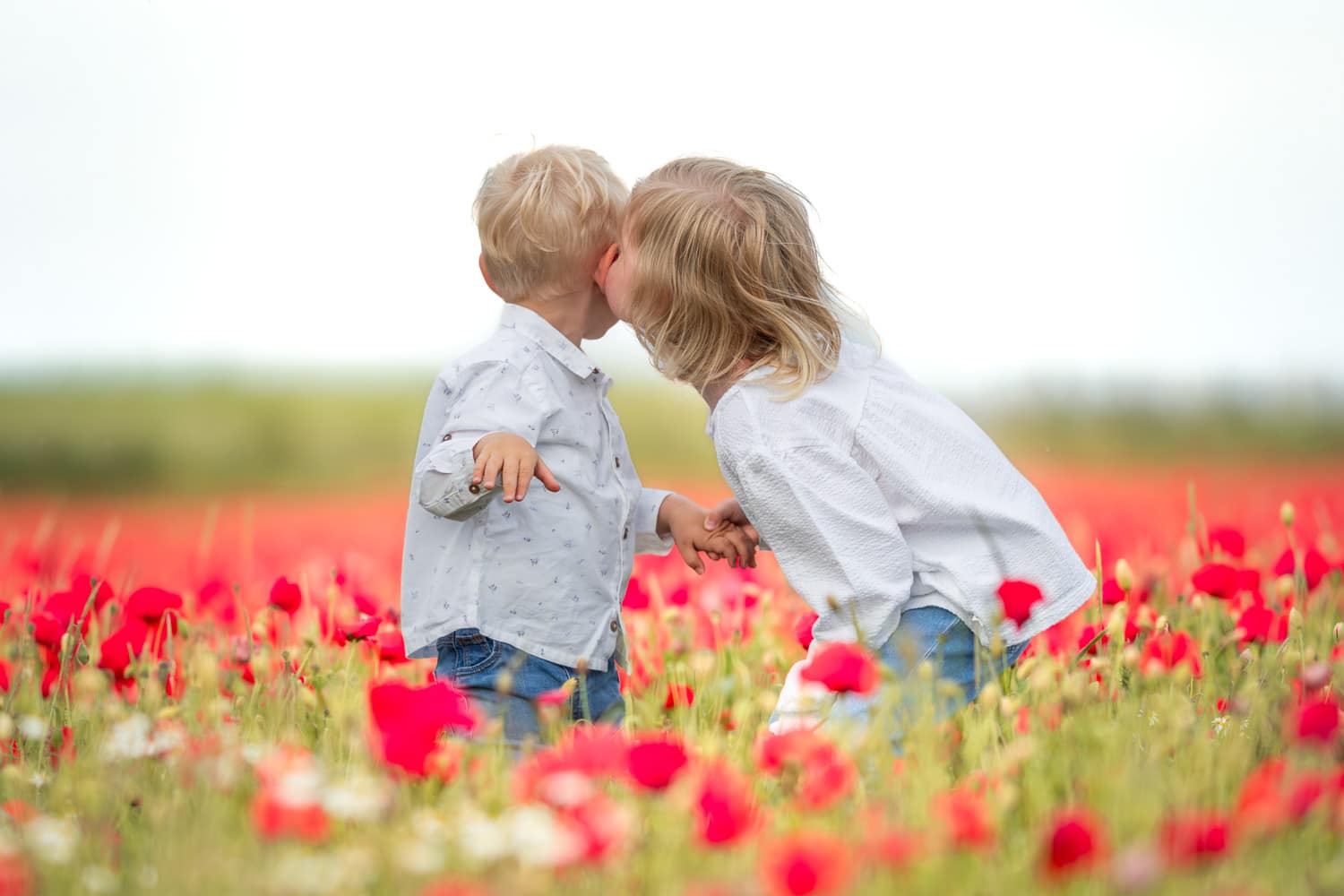 portrait de deux enfants jouants dans un champs de coquelicot